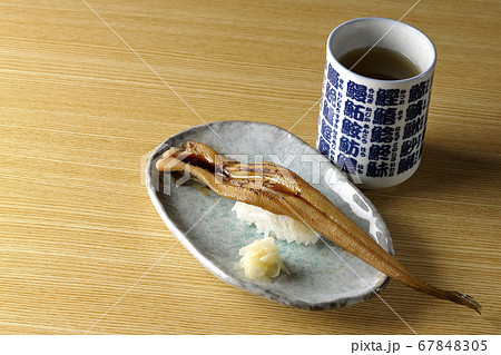 お皿の上に盛り付けられた炙り煮穴子の一本握りとお茶 お皿の上に盛り付けられた炙り煮穴子の一本握りとお茶 67848305