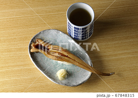 お皿の上に盛り付けられた炙り煮穴子の一本握りとお茶 お皿の上に盛り付けられた炙り煮穴子の一本握りとお茶 67848315