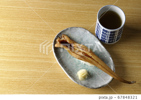 お皿の上に盛り付けられた炙り煮穴子の一本握りとお茶 67848321