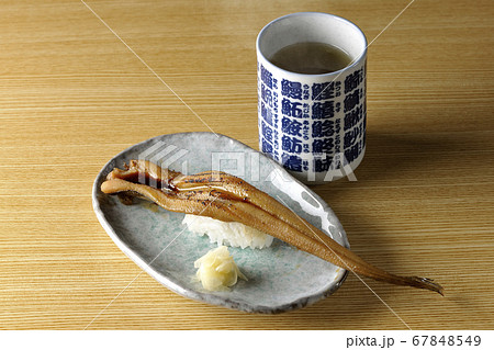 お皿の上に盛り付けられた炙り煮穴子の一本握りと熱々のお茶 お皿の上に盛り付けられた炙り煮穴子の一本握りと熱々のお茶 67848549