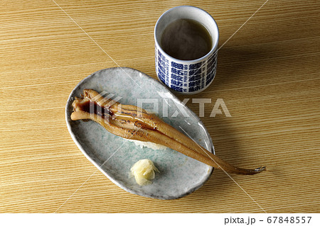 お皿の上に盛り付けられた炙り煮穴子の一本握りと熱々のお茶 お皿の上に盛り付けられた炙り煮穴子の一本握りと熱々のお茶 67848557
