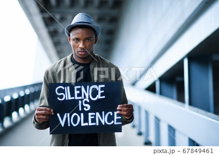 Man with silence is violence sign standing outdoors, black lives matter concept. Man with silence is violence sign standing outdoors, black lives matter concept. 67849461