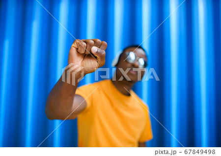 Black man with raised fist standing against blue background, black lives matter concept. 67849498