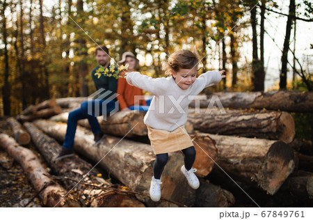Small girl with parents on a walk in autumn forest, jumping. 67849761
