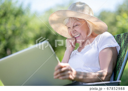Concentrated elderly woman texting her friends via the laptop 67852988