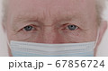 Macro portrait of wrinkled senior man with mask blinks into the camera 67856724