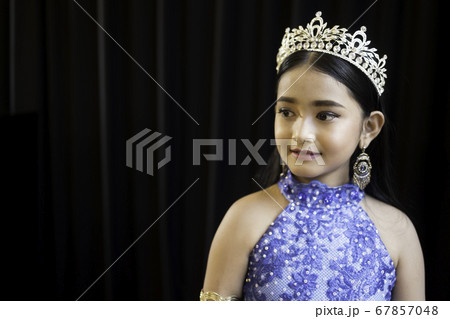 Portrait of a cute Asian girl, makeup, wearing a blue evening dress and a crown. 67857048