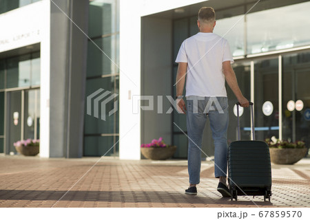 Male tourist walking with baggage at airport terminal 67859570