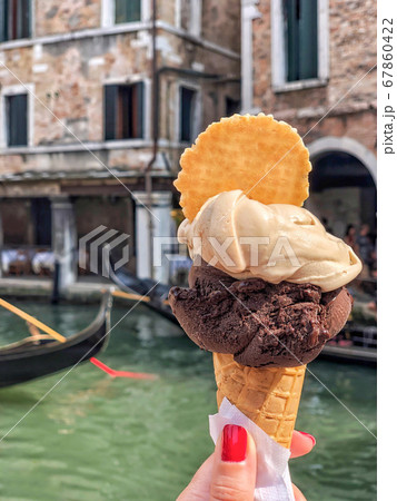 hand holding ice cream over gondolas in canal of 67860422