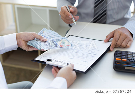 Businessmen make dollar payments while signing an investment agreement to be a partner in an illegal and successful manner, Bribery and corruption concept. 67867324