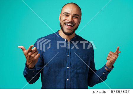 Joyful dark-skinned man laughing against turquoise background Joyful dark-skinned man laughing against turquoise background 67867337