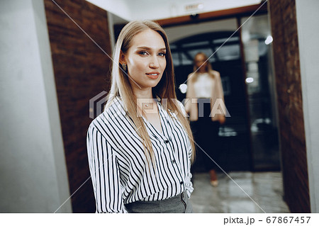 Two young women in formal clothes entering hotel lobby 67867457