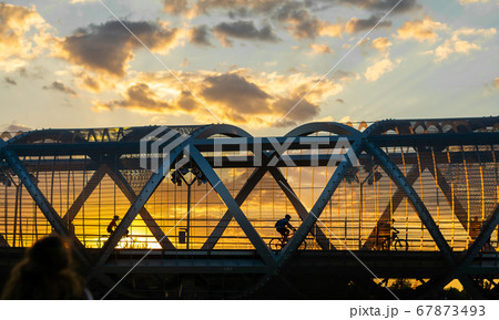 Cylists cross the bridge in the evening, sunset time , Arganzuela Footbridge, Puente de Arganzuela in Madrid 67873493