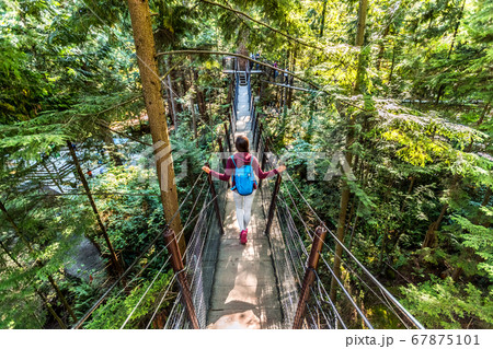 Canada travel tourist woman walking in famous attraction Capilano Suspension Bridge in North Vancouver, British Columbia, canadian vacation destination for tourism Canada travel tourist woman walking in famous attraction Capilano Suspension Bridge in North Vancouver, British Columbia, canadian vacation destination for tourism 67875101