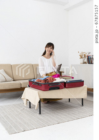 スーツケースに荷物を詰めて旅行の準備をする若い女性 スーツケースに荷物を詰めて旅行の準備をする若い女性 67875157