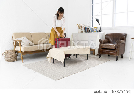 キャリーバッグに荷物を詰めて出かける準備をする女性 67875456