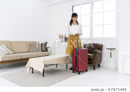キャリーバッグに荷物を詰めて出かける準備をする女性 67875466
