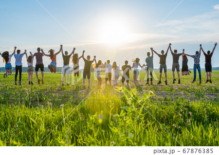 Friends are jumping holding hands at sunset. Friends are jumping holding hands at sunset. 67876385