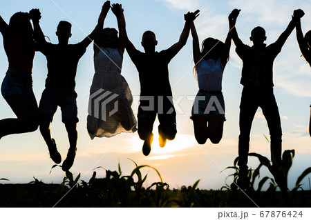 Silhouettes Of Jumping Friends On A Sunset の写真素材