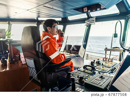 Filipino deck Officer on bridge of vessel or ship. He is speaking on GMDSS VHF radio Filipino deck Officer on bridge of vessel or ship. He is speaking on GMDSS VHF radio 67877508