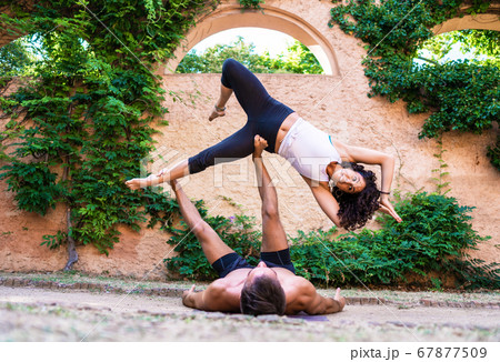 Two beautiful women doing acroyoga in the garden or park Two beautiful women doing acroyoga in the garden or park 67877509