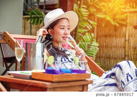 Beautiful young woman lying on a deckchair with a Beautiful young woman lying on a deckchair with a 67885017