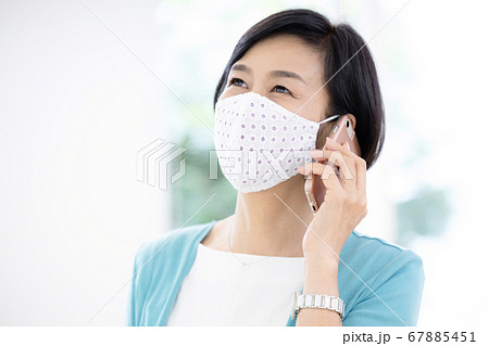 ミドル女性　おしゃれなマスクを着用し電話をする女性 67885451