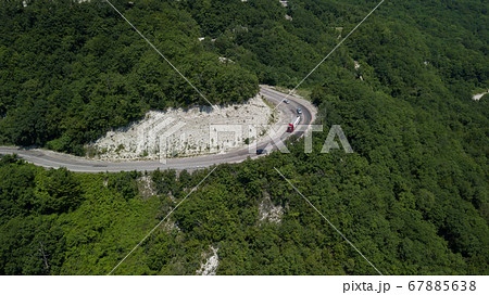 Aerial view from drone of curve road with a car on the mountain with green forest in Russia 67885638