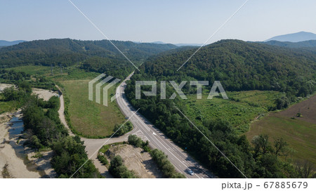Aerial view from above of curve highway road with a car with green forest in Russia Aerial view from above of curve highway road with a car with green forest in Russia 67885679