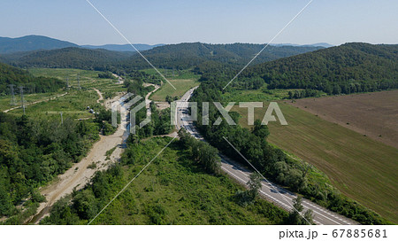 Aerial view from above of curve highway road with a car with green forest in Russia Aerial view from above of curve highway road with a car with green forest in Russia 67885681
