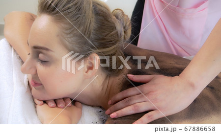 Relaxed woman lying on spa bed for body scrubbing. Relaxed woman lying on spa bed for body scrubbing. 67886658