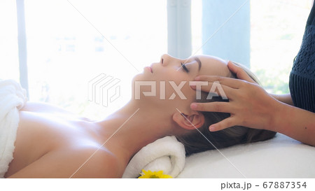 Woman gets facial and head massage in luxury spa. 67887354