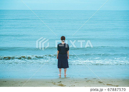 波打ち際に立つ女性　後ろ姿　雨天　 67887570