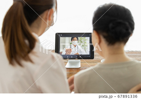 オンライン診療を受けるシニア女性とそのケアスタッフ、及び通話アプリで繋がっている医師 67891336