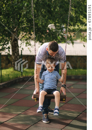 Little boy on the swing. Happy kid outdoors with dad Little boy on the swing. Happy kid outdoors with dad 67893191