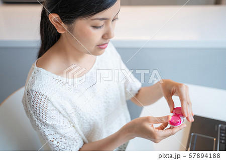 コンタクトレンズをつけようとしてる若い女性 67894188