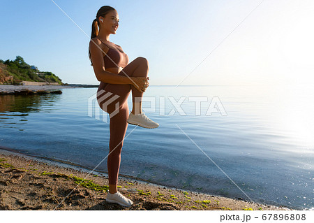 Smiling girl preparing for cardio workout, stretching leg 67896808