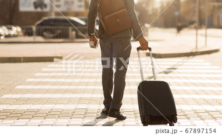 Unrecognizable Gentleman With Travel Suitcase Crossing Road Outdoor, Panorama, Rear-View Unrecognizable Gentleman With Travel Suitcase Crossing Road Outdoor, Panorama, Rear-View 67897154