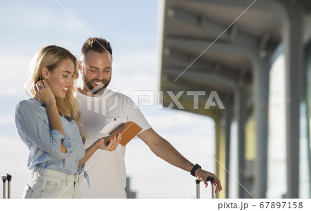 Travel concept. Young couple checking tickets outside Travel concept. Young couple checking tickets outside 67897158