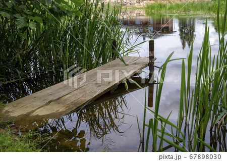 Old rustic wooden jetty on a tranquil lake 67898030