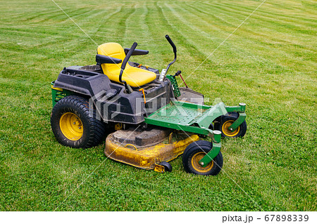 Dirty lawnmower after work on green grass in sunny day. Freshly cut grass by lawnmower. Gardening concept background Dirty lawnmower after work on green grass in sunny day. Freshly cut grass by lawnmower. Gardening concept background 67898339