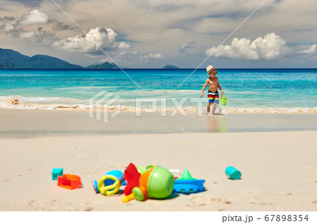 Three year old toddler playing on beach Three year old toddler playing on beach 67898354