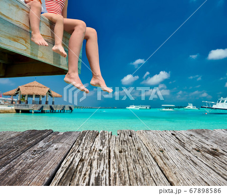 Toddler boy with mother sitting on wooden jetty 67898586