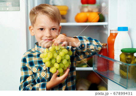 Little boy standing in front of open fridge and choosing food Little boy standing in front of open fridge and choosing food 67899431