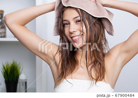 Woman with beautiful long hair wipes her head with a soft towel 67900484