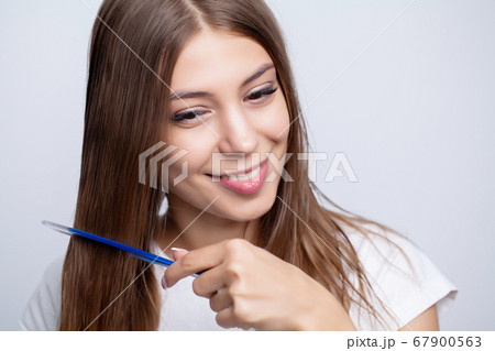 A young girl with beautiful long hair uses a com 67900563