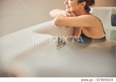 Smiling dark-haired lady enjoying a water procedure Smiling dark-haired lady enjoying a water procedure 67900929