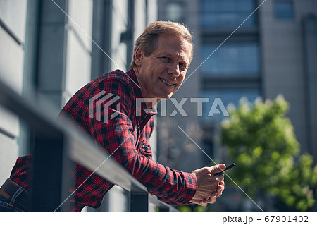 Cheerful man with cellphone standing on the street Cheerful man with cellphone standing on the street 67901402