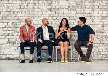 Beautiful cheerful professional woman wearing eyeglasses seated with male co-workers and team leader at work Beautiful cheerful professional woman wearing eyeglasses seated with male co-workers and team leader at work 67902790