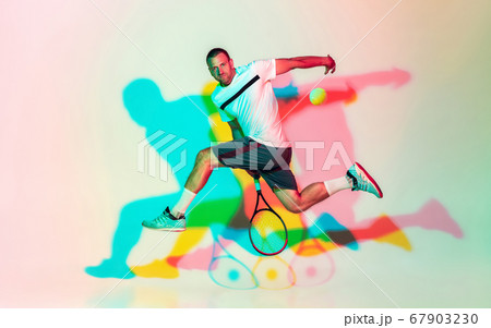 Caucasian male professional sportsman playing tennis on studio background in neon light 67903230